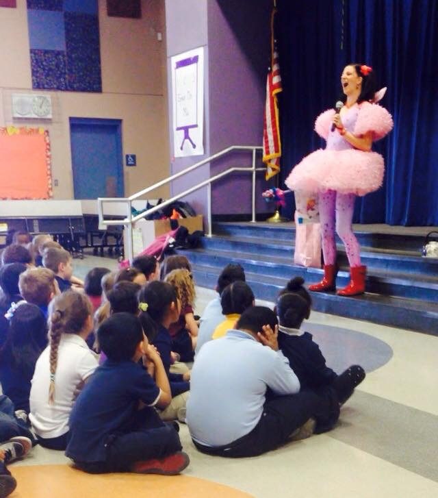 Keri performing in a pink flamingo costume for seated students.